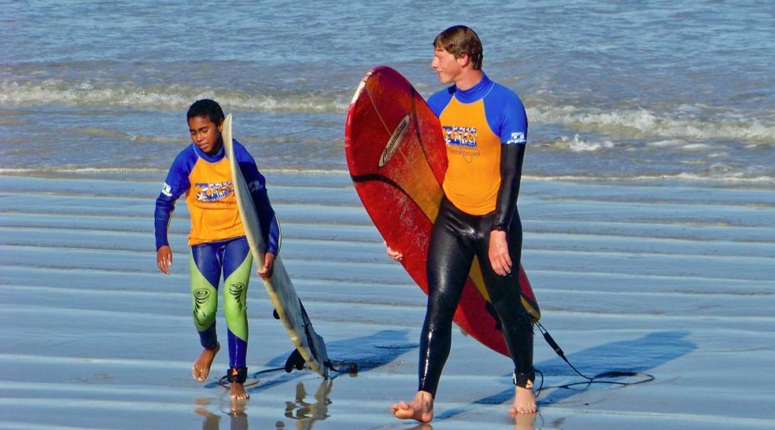 Volunteer walks with a boy in a surf project in South Africa Volunteer walks with a boy in a surf project in South Africa